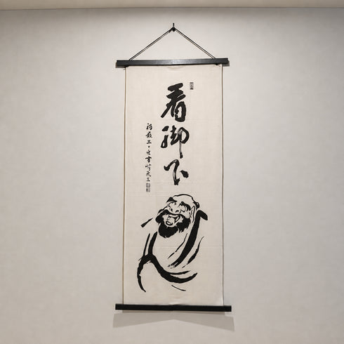 壁に飾った笑うダルマさん手ぬぐい